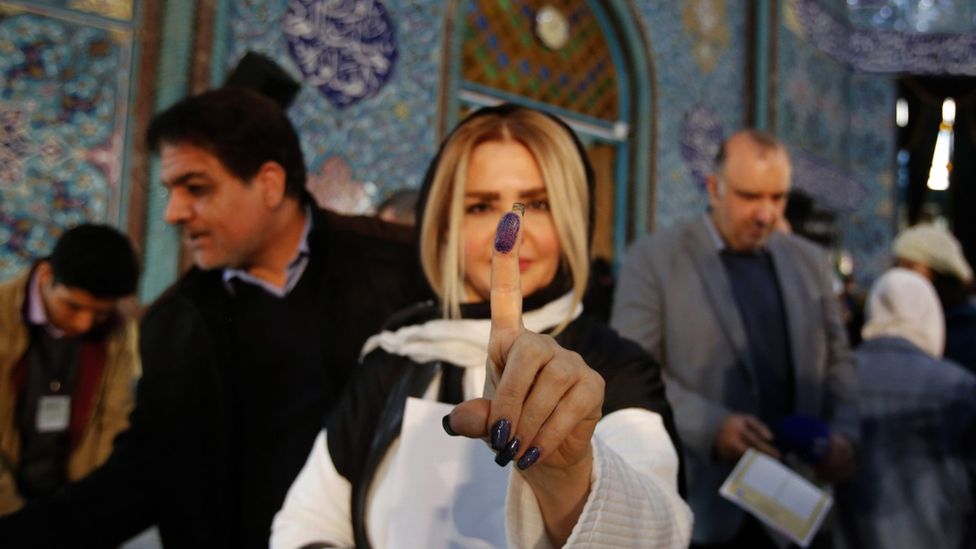 An Iranian woman shows her ink covered finger after she cast her vote in the Iranian legislative election at Ershad mosque in northern Tehran