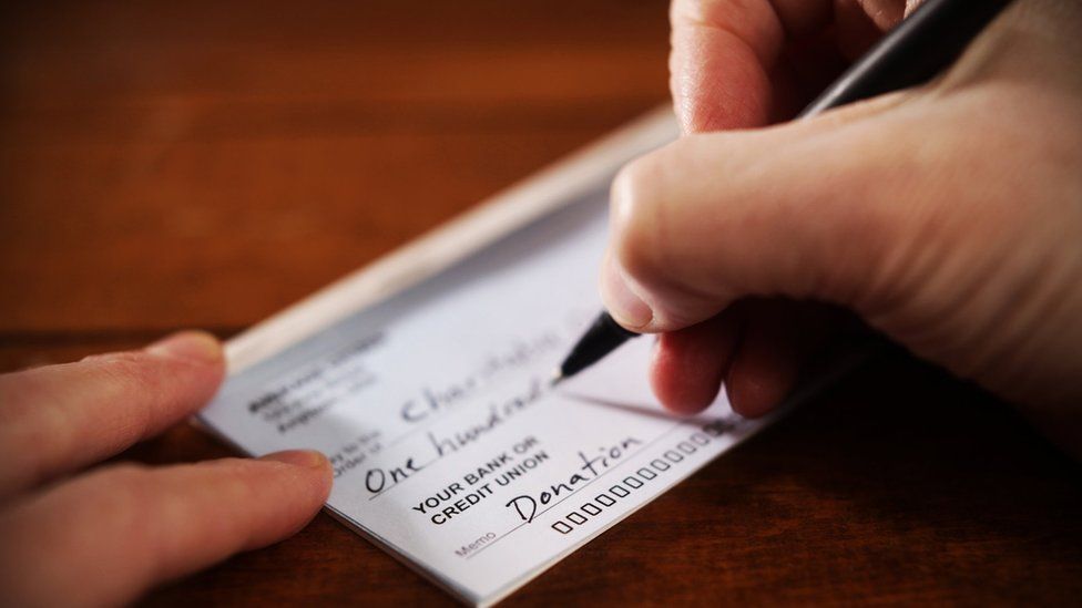 A person writes a donation cheque in this close-up photo