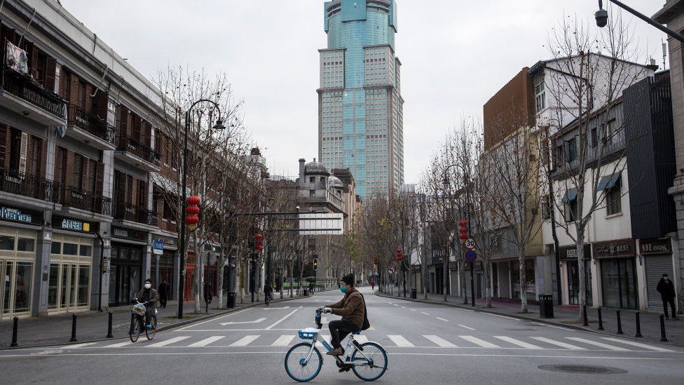 A man by bicycles past an empty street on February 8, 2020 in Wuhan, Hubei province, China.