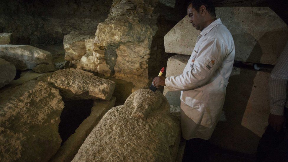 Un arqueÃ³logo egipcio trabaja en un sarcÃ³fago en la reciente necrÃ³polis descubierta.