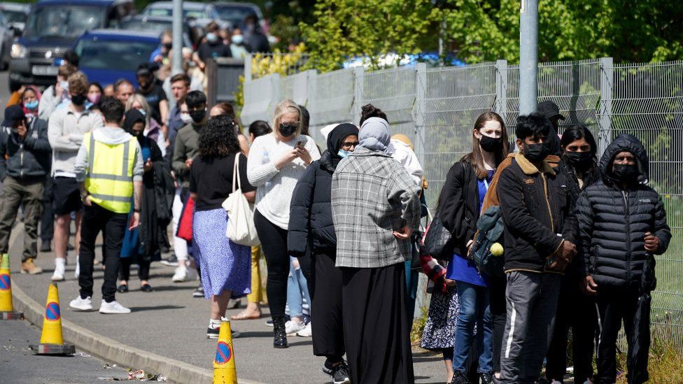 People queue for Covid-19 vaccinations at the ESSA academy in Bolton where mass vaccinations are taking place to try and combat rising levels of the Indian coronavirus variant on May 18, 2021 in Bolton, England.