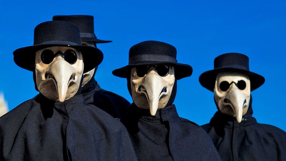A group of people in plague doctor masks at the Venice Carnival