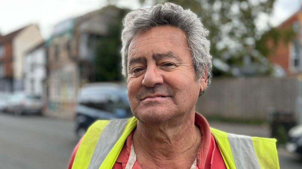 A man with white hair in a hi-vis jacket