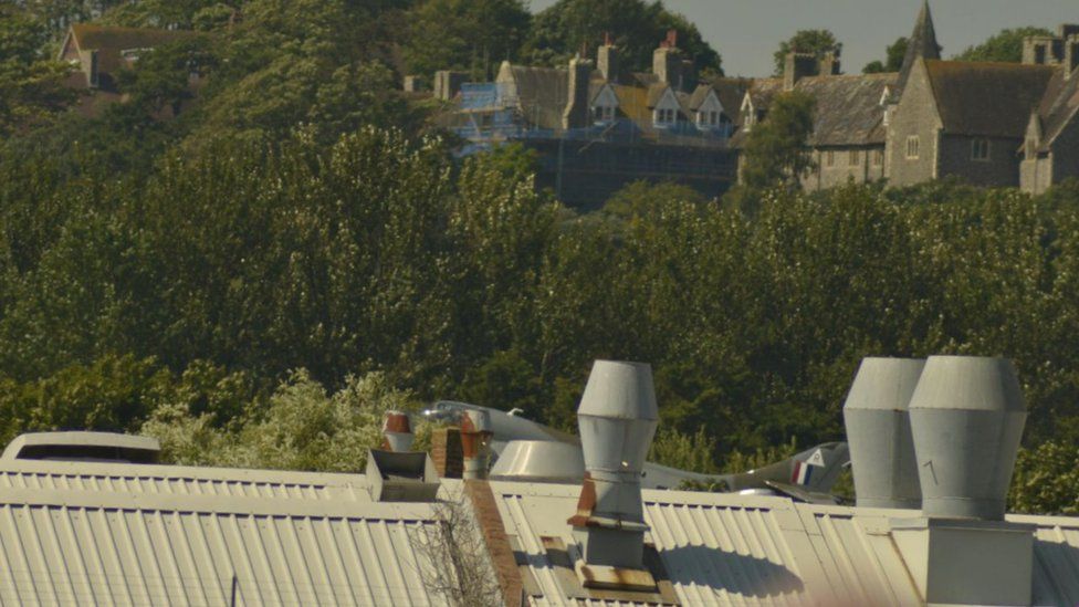 The plane just visible at the roofline of nearby buildings