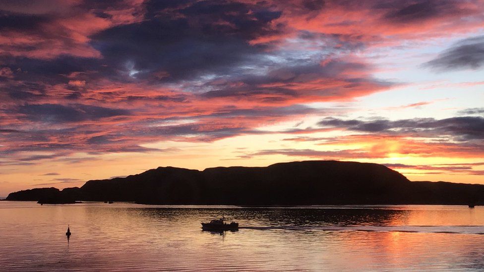 A sunset over Oban Bay with boat in forefront