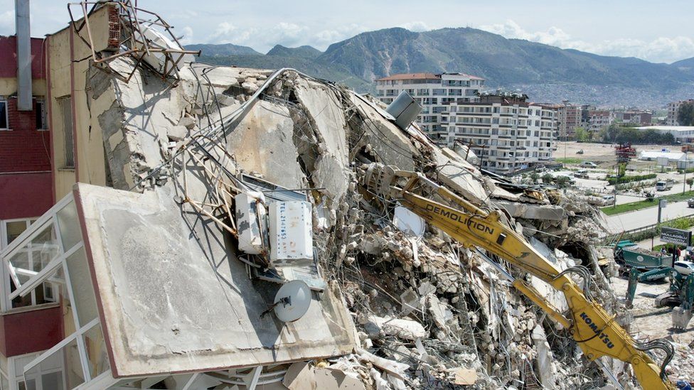 Землекоп работает на обломках рухнувшего здания в Антакье