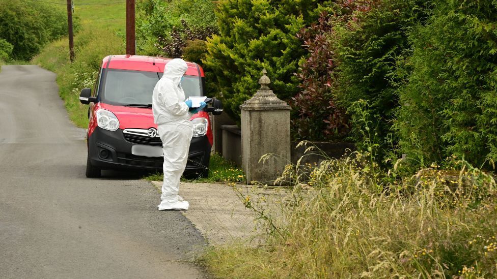 Person in forensic white suit on the road writing on a paper pad 