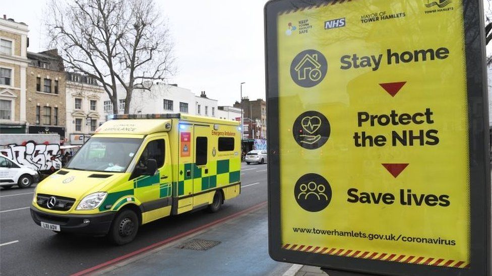 An ambulance passes a coronavirus poster in east London