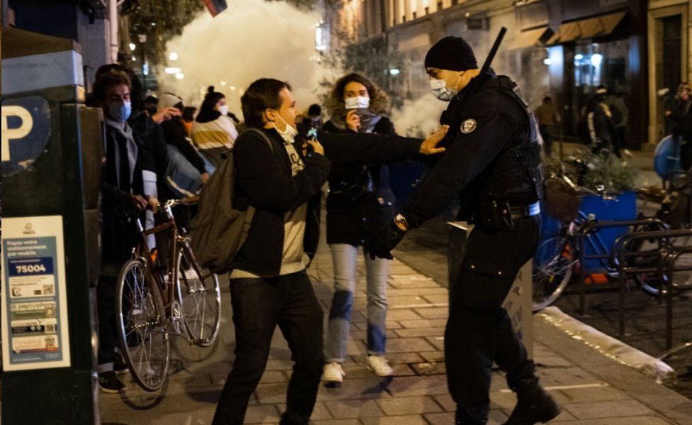 Protester and policeman in street in Paris, with tear gas cloud, 23 Nov 20