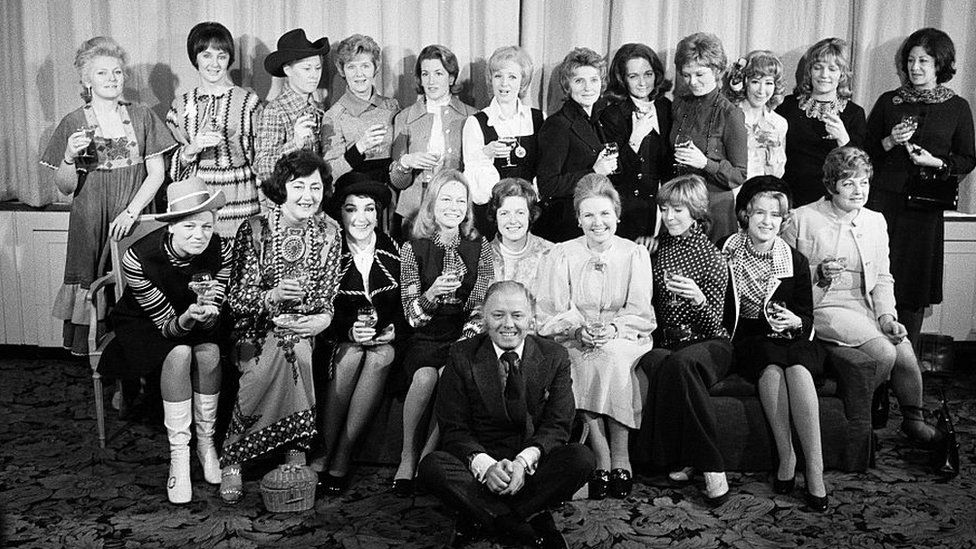 Attenborough and Sim posing with 20 of the show's leading ladies
