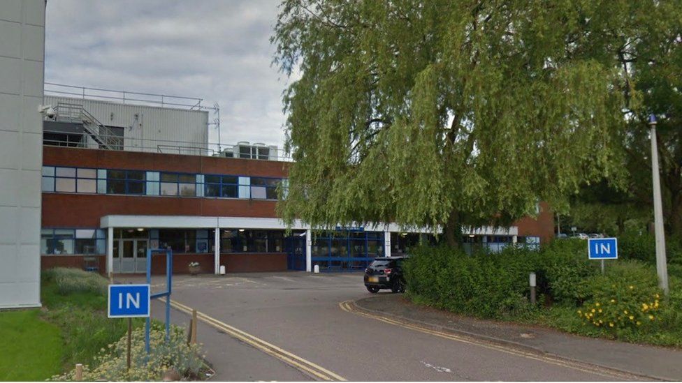 Two-storey brick and concrete building behind large tree