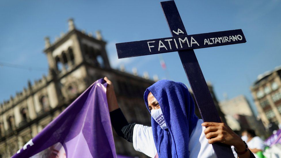 A woman holds a cross as relatives and friends of victims of femicide take part in a march in Mexico City