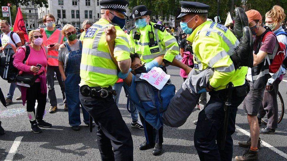 An activist from the climate protest group Extinction Rebellion is carried away by police officers