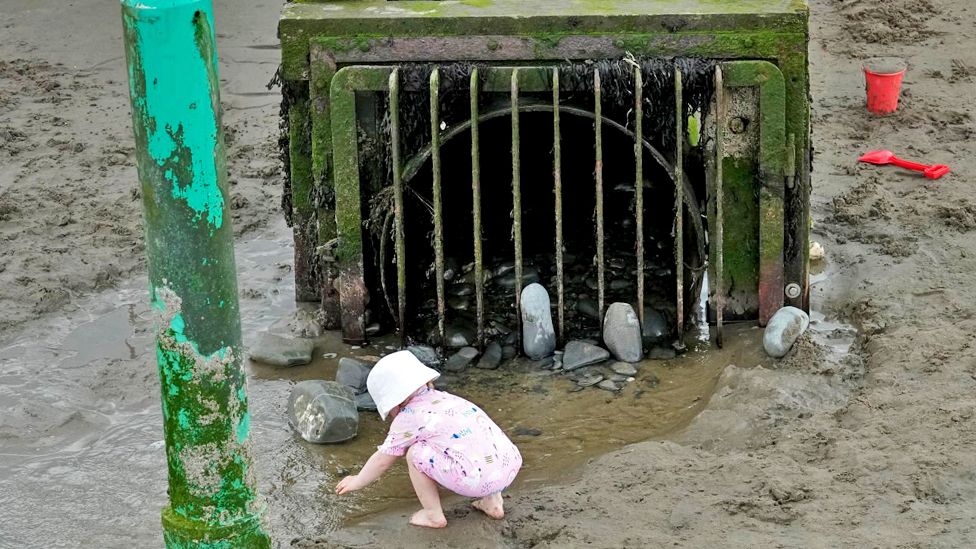 A child plays on Borth Beach next to a storm overflow pipe that discharges into the sea on 10 August 2023 in Borth, Wales