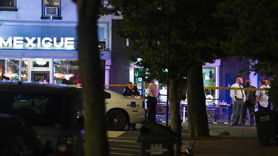 Police officers stand outside a restaurant after a shooting in Washington, DC, on July 22, 2021