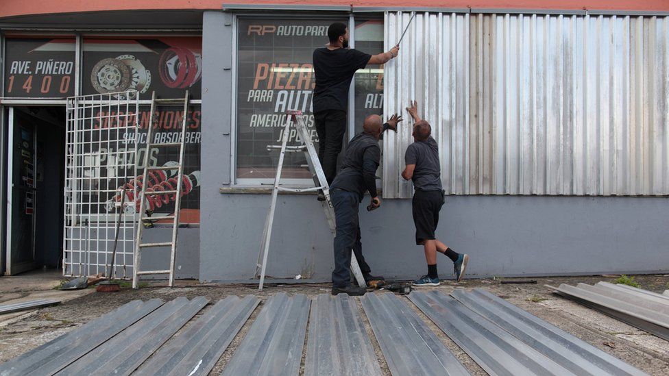 Men cover the windows of a car parts store in preparation for Hurricane Irma in San Juan
