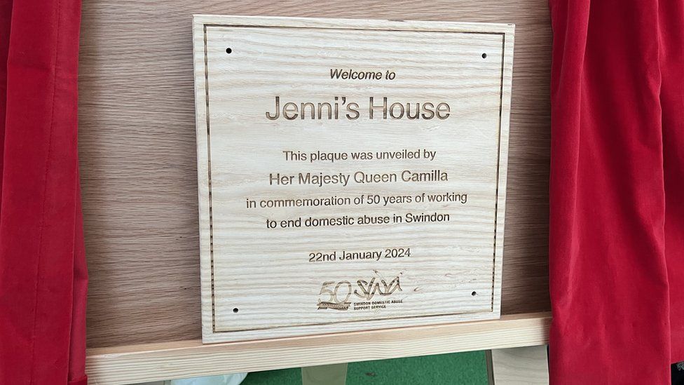Wooden plaque which reads 'Welcome to Jenni's House. This plaque was unveiled by Her Majesty Queen Camilla in commemoration of 50 years of working to end domestic abuse in Swindon'.