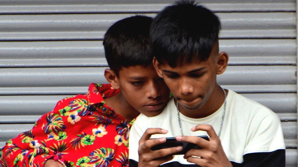 Children watch a mobile screen in Mumbai, India.