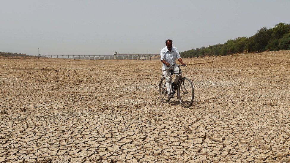 An Indian cyclist rides along dry bed of Sabarmati river near the Sant Sarovar, a reservoir situated in Gujarat's capital Gandhinagar, some 30 Kms. from Ahmedabad on May 1, 2019.