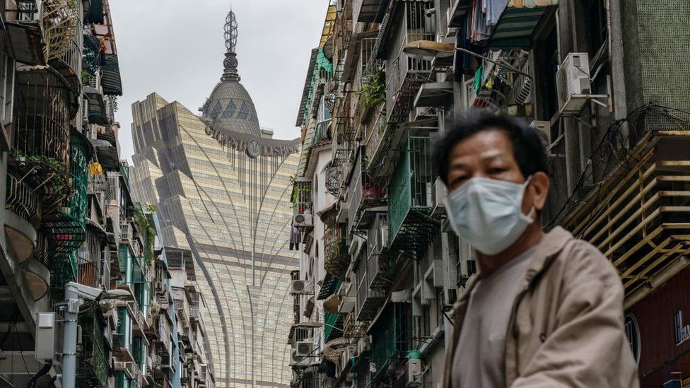 A man wearing protective mask walks across a street in front of the Grand Lisboa Hotel in a residential district on February 5, 2020 in Macau, China