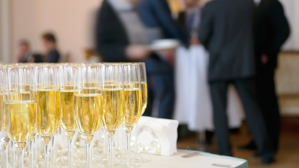 Champagnes glasses on table in front of men in suits