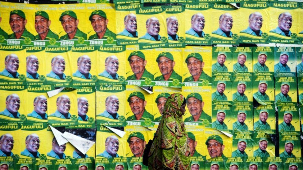 A woman walks past posters for ruling party Chama Cha Mapinduzi (CCM) presidential candidate John Magufuli
