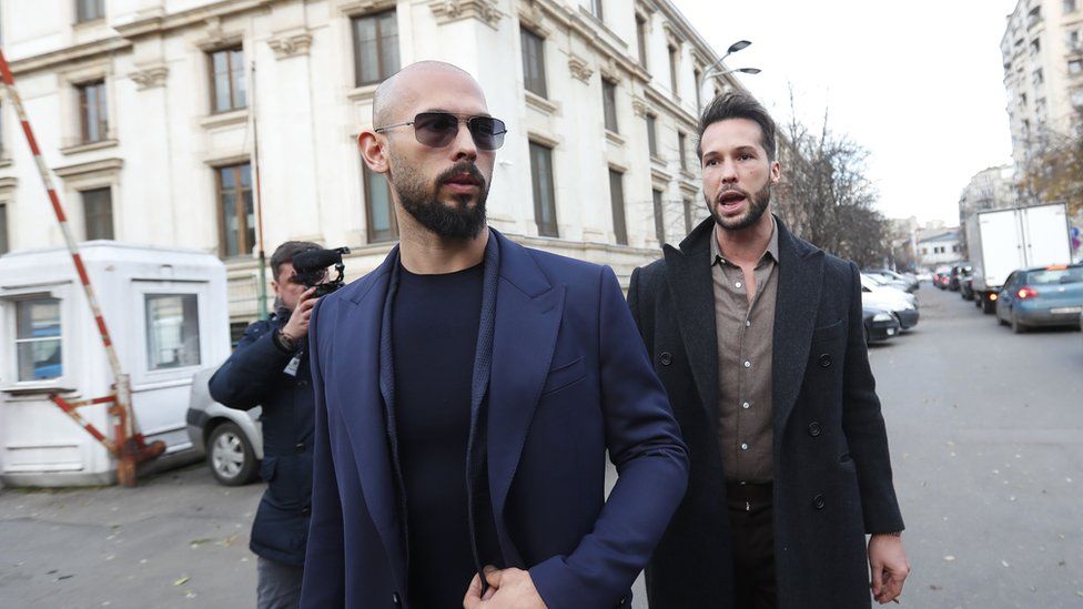 The Tate brothers appearing at court. Andrew is in the front with a bald head and sunglasses, and his brother Tristan is standing behind him