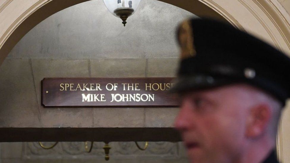 O nome de Mike Johnson em letras douradas novas e brilhantes acima da porta do Orador