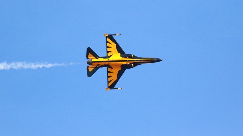 Yellow and black military plane in the sky, tilted vertically