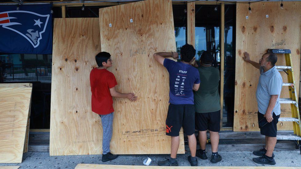 Workers place protective plywood over the openings at Toucan's Bar & Grill before the possible arrival of Hurricane Idalia on August 29, 2023 in Clearwater Beach, Florida
