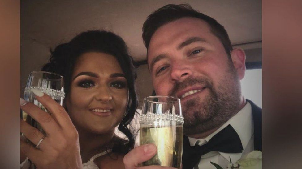 Samantha Willis and Josh Willis pictured on their wedding day, both holding glasses of champagne