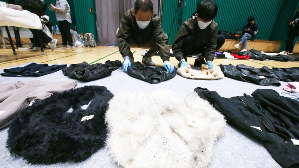 Police officers check clothes collected from the scene of an stampede, at a multi-purpose gym in Seoul, South Korea,