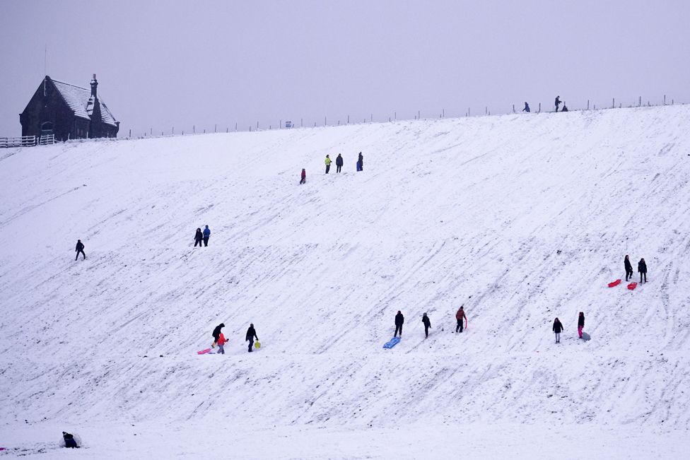 People sledge down a hillside at Butterley Reservoir in Marsden, West Yorkshire, on 14 January 2021