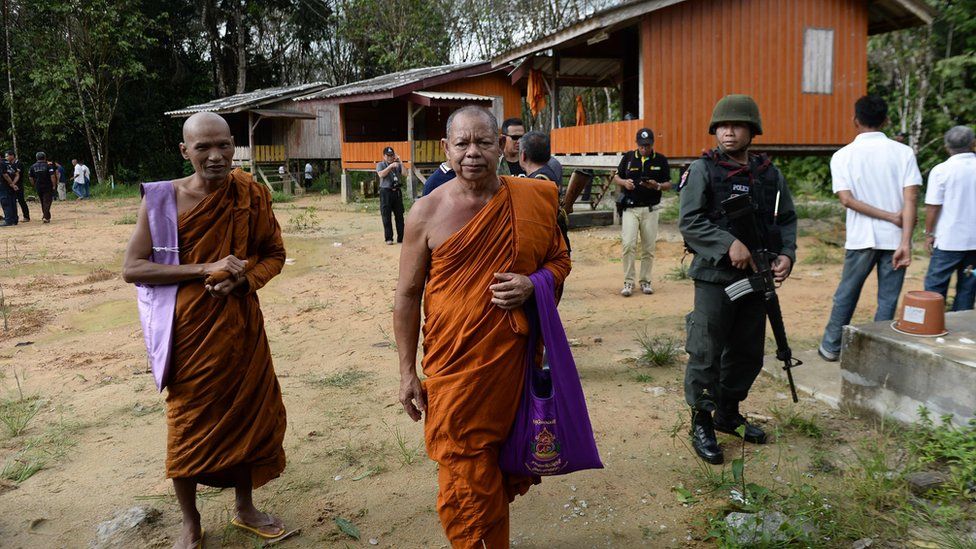 Buddhist monks pass an armed Thai police officer assigned with securing the compound of Rattanaupap temple in Narathiwat province, 19 January 2019