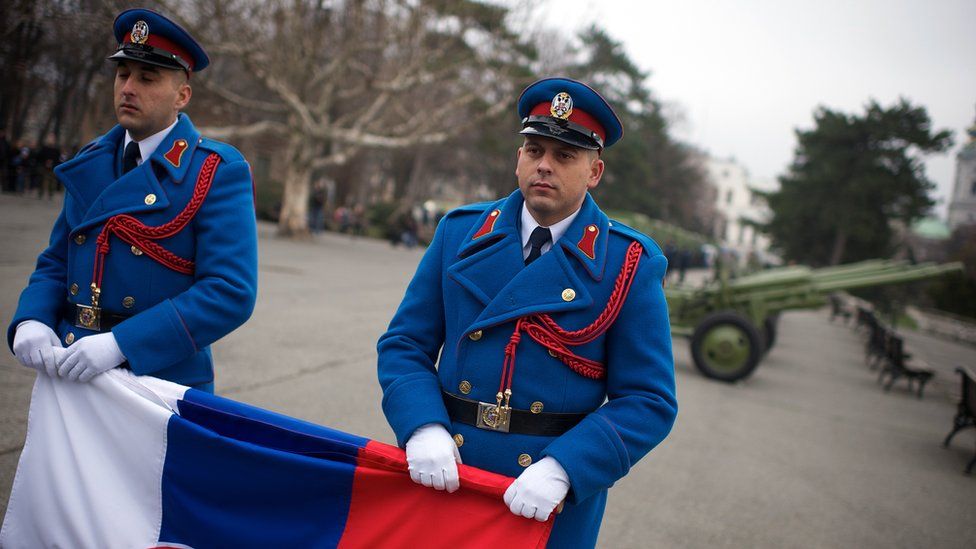 Soldiers hold the national flag as part of Serbia's Statehood Day celebrations