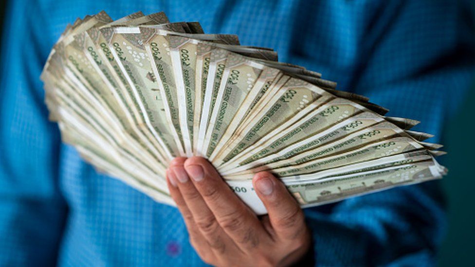 Man holding a wad of 500-rupee notes