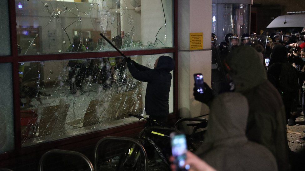 A protester smashes the window of Bridewell Police Station