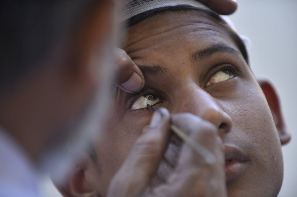 A herbal eye-liner is applied to the eyes of a Muslim