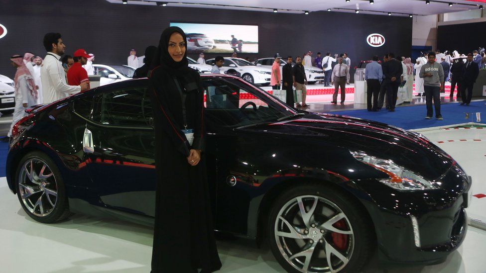 A hostess and visitors attending the Saudi International Motor Show on 13 Dec 2015 in Jeddah