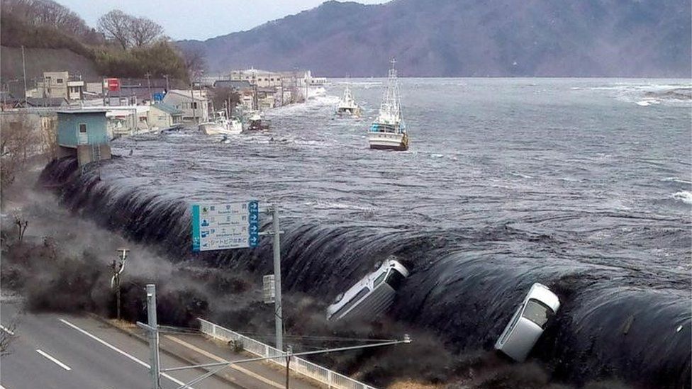 Tsunami breeching an embankment and flowing into the city of Miyako in 2011