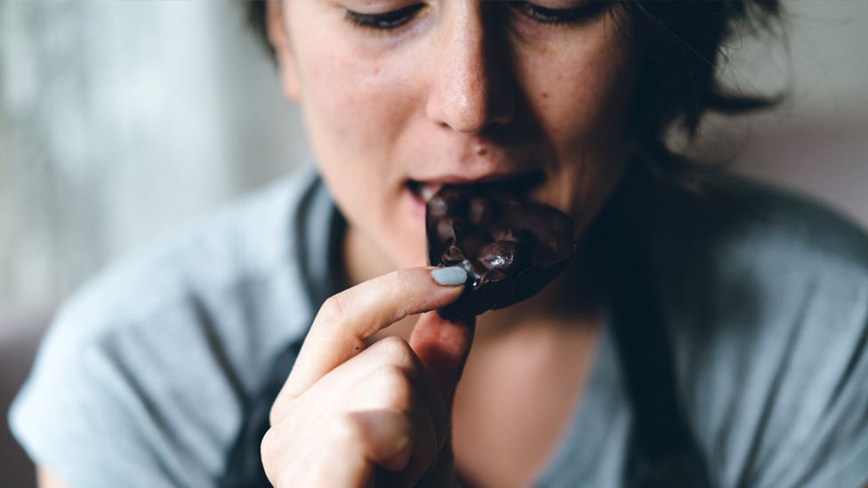 A woman eats a piece of chocolate