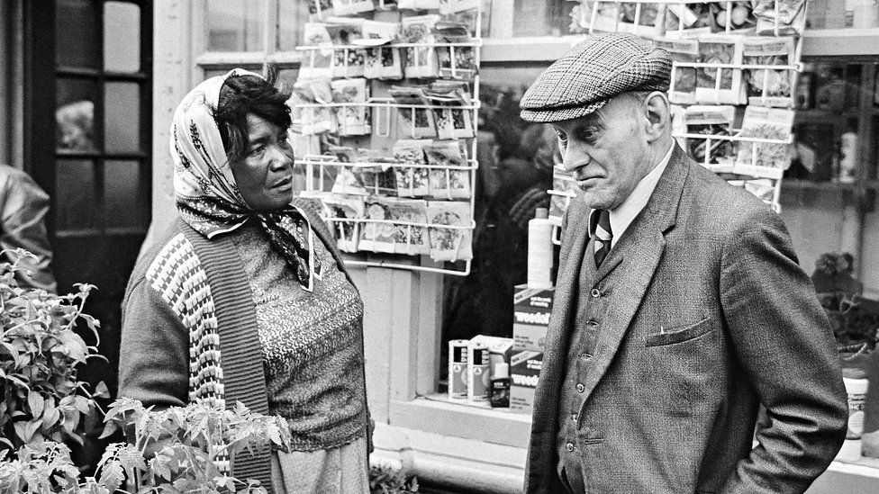 Woman and man engaged in conversation by some plants