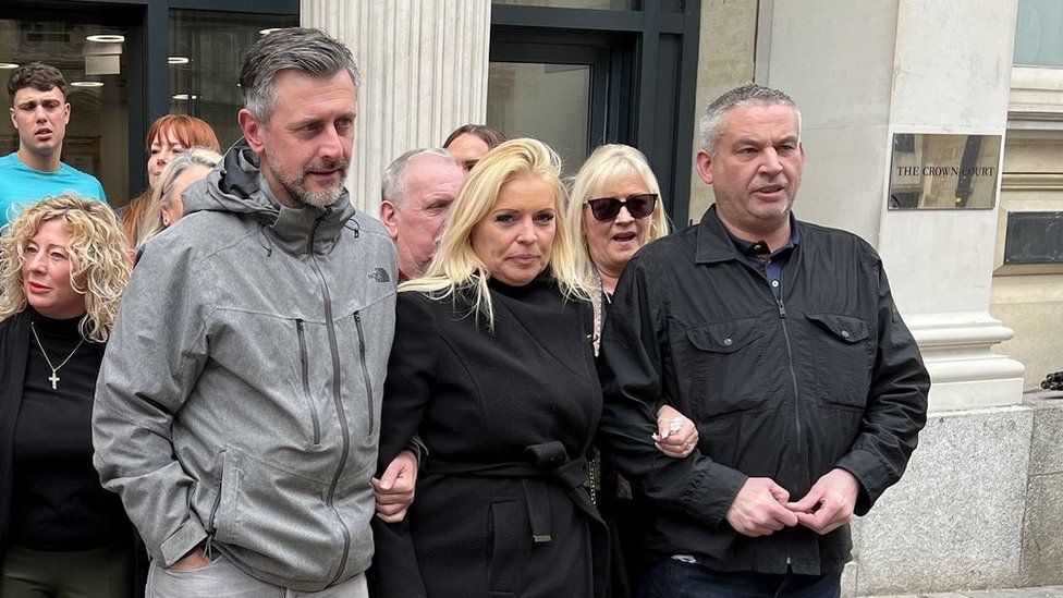 A blonde woman stood with two men outside court