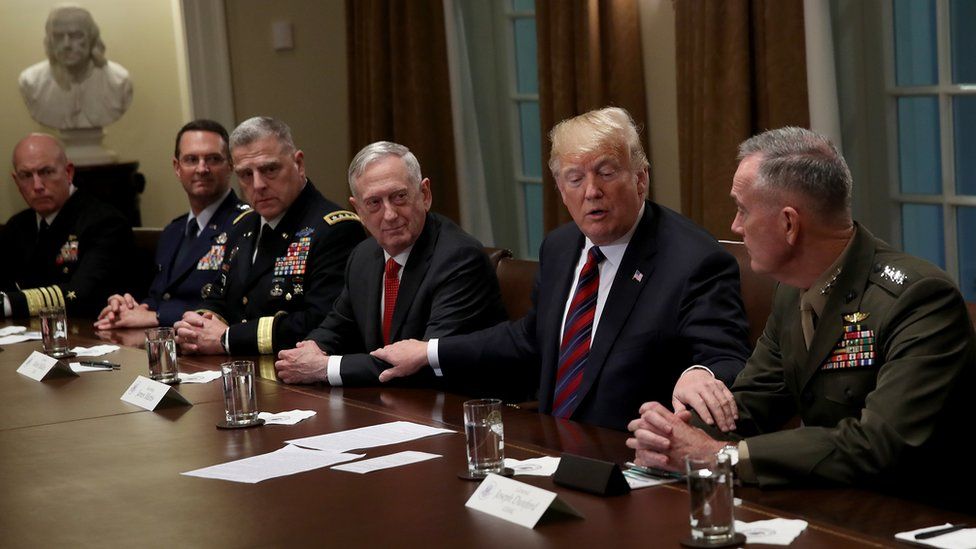 U.S. President Donald Trump reaches out to touch the arms of Chairman of the Joint Chiefs of Staff Joseph Dunford (R) and U.S. Defense Secretary Jim Mattis (C) while delivering remarks during a meeting with military leaders