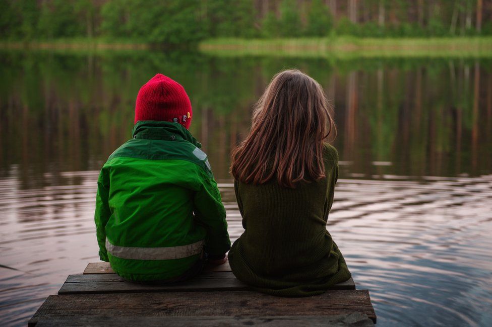 A boy and girl sit on a pier