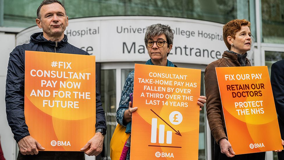 Three consultants hold orange placards outside UCLH on 19 September 2023