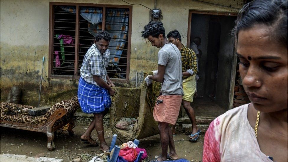 A family try to clean up their flooded house in Mundancavu village in Kerala, India