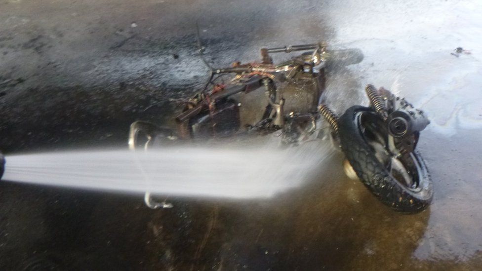 Burnt remains of a motorbike dowsed with water