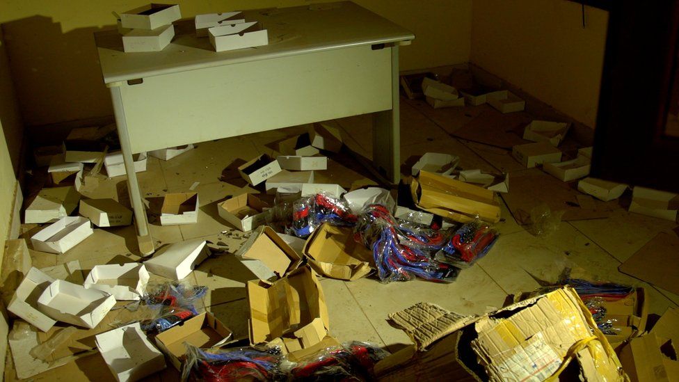 Boxes and electronic equipment are strewn on the floor of an office