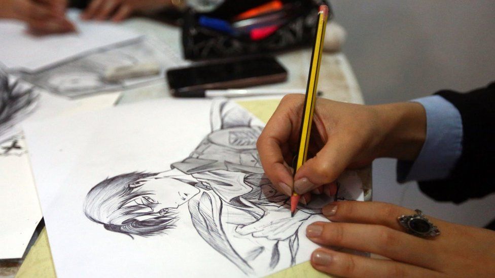 An artist draws a manga-style illustration at a stall during the Libya Comic Convention, in the capital Tripoli on 2 November 2017